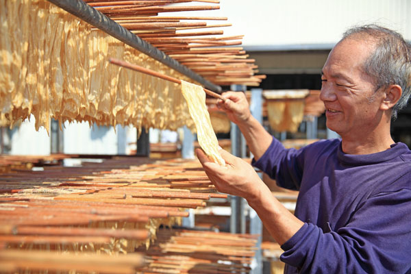宋新富在日晒的過程中逐一檢示每片豆皮 Mr. Song checks each piece throughout the drying process.