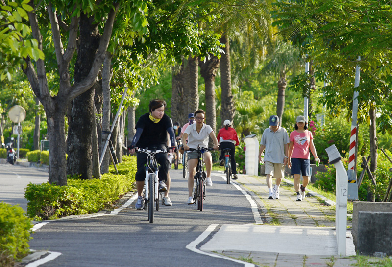 騎乘在綠樹成蔭的高雄自行車道上悠閒又逍遙。（圖∕張簡英豪 攝）