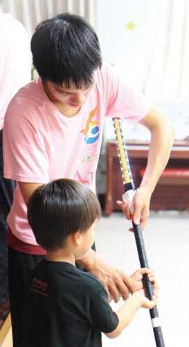 火舞社員教導永安之家小朋友運轉LED棍棒。Touring members teach how to grasp LED-lit sticks at Yongan Children's Home