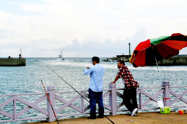在南寮漁港旁，悠閒的釣客透過釣竿與海洋交流。(圖/黃建樺 攝)