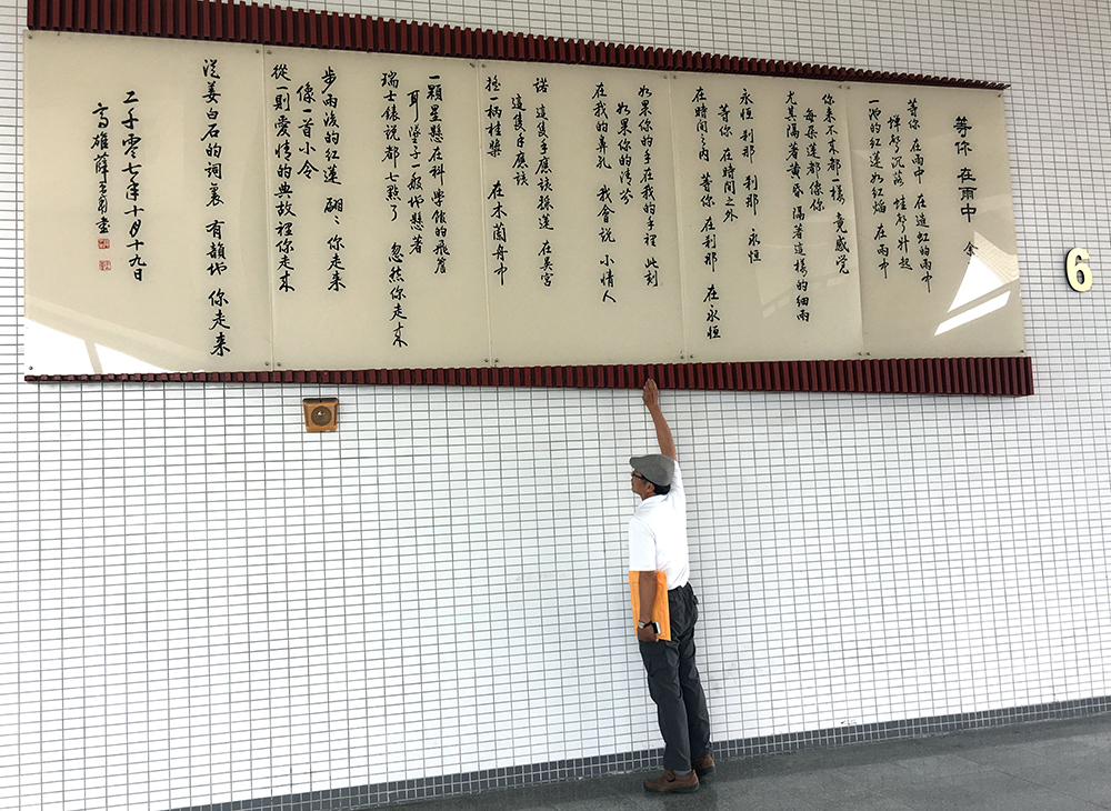 位於禮堂外牆巨幅的詩壁，呈現由名書法家薛平南書寫余光中的詩-等你 在雨中。(攝影/李幸潔)