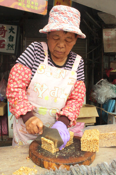 余媽媽熟練地將花生糖切塊，現場香味四溢。（圖/方昭禪　攝）