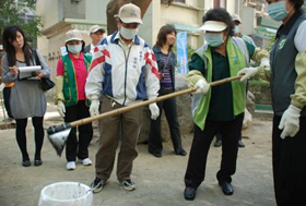 戴上口罩、手套，陳菊市長手持工具，親自動手示範清理屋後溝。(圖／郭力睿攝)