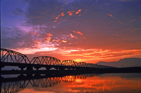 夕陽餘暉下更顯歷史痕跡的舊鐵橋，圓弧造型倒映河面相當優美。(圖/大樹區公所提供)
