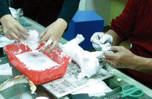 2.以紗布塊沾取石膏糊在心棒外，一層層塑形。Layering the armature with plaster gauze.